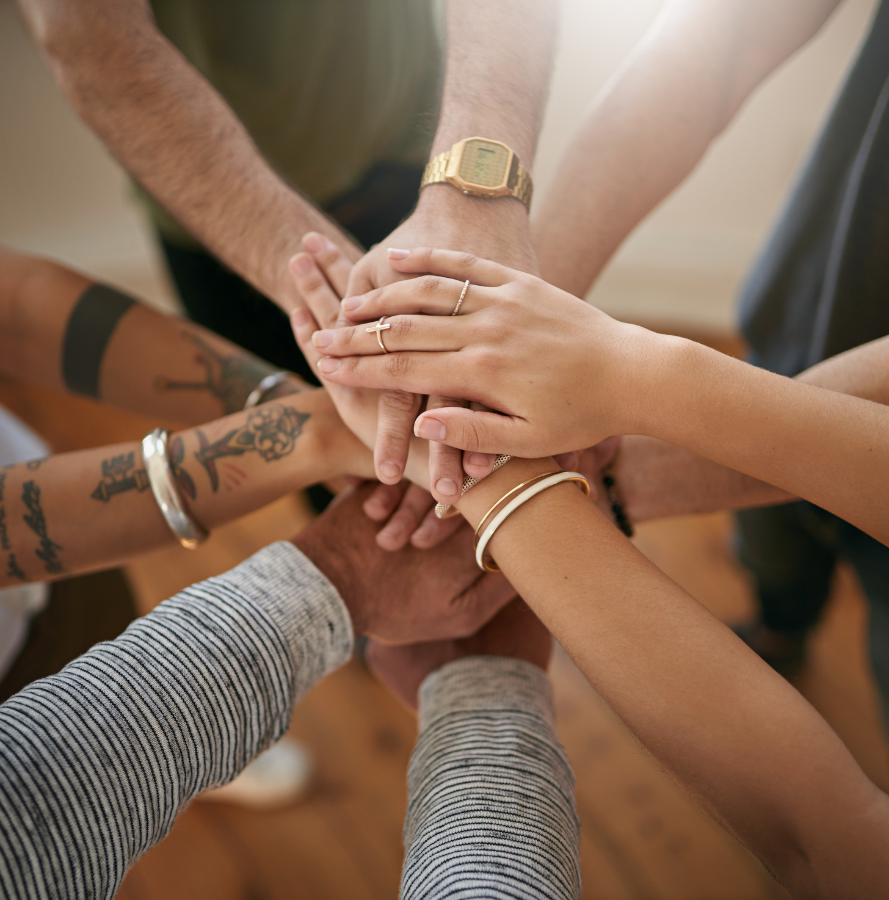 Alt text: A diverse group of people stacking hands in a show of unity.
