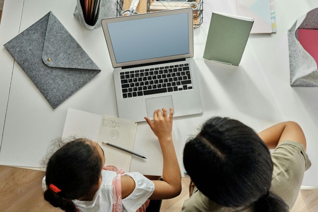 Two people look at a computer and doing homework
