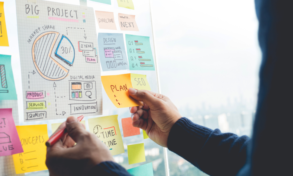 Person organizing notes and charts on a glass wall, planning a big project with diagrams, timelines, and strategy notes, representing the mentoring strategy plan.