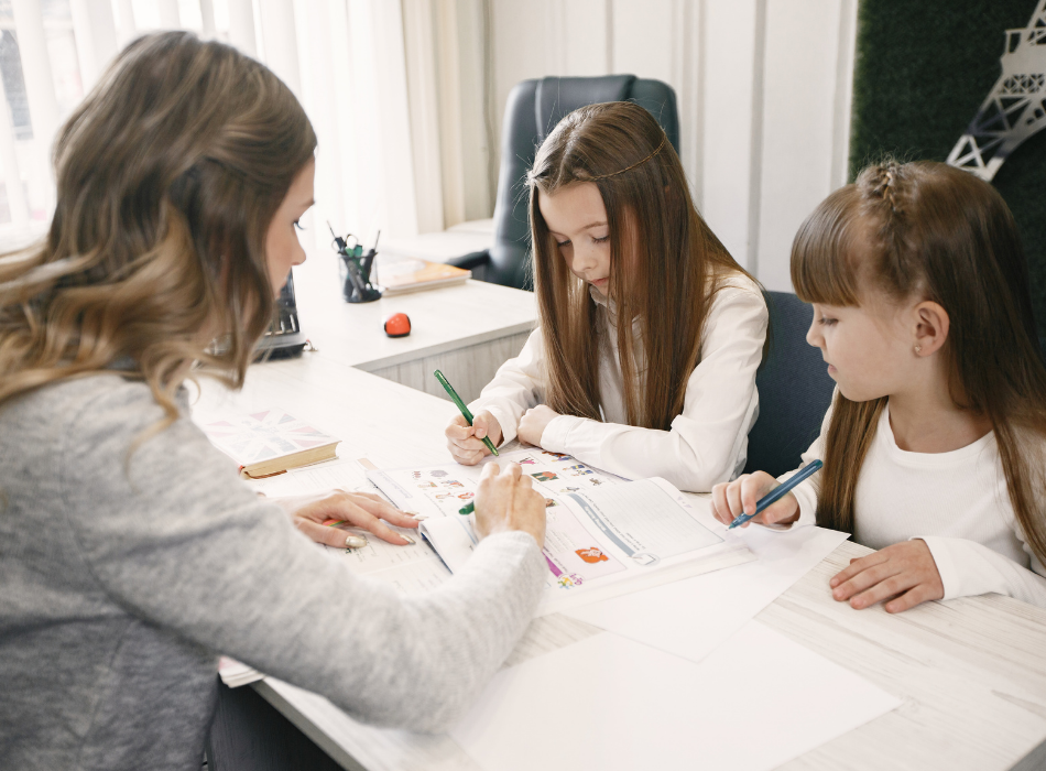 An alumni mentor is mentoring two K12 students at a table