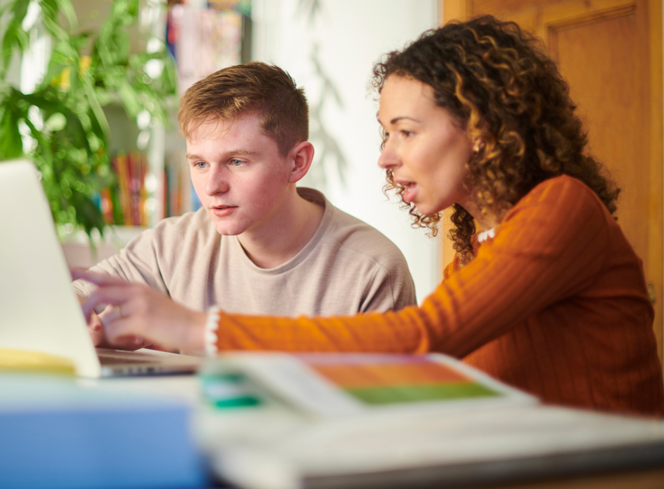 An alumni mentor and K12 mentee and sitting at a table looking at a computer