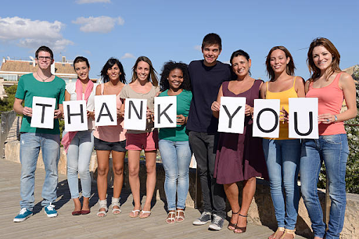 Current students smiling and holding handmade thank-you posters for alumni supporters.