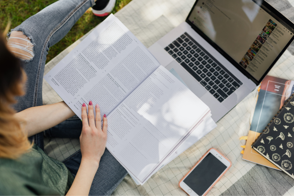 Woman working on school work with textbook and computer