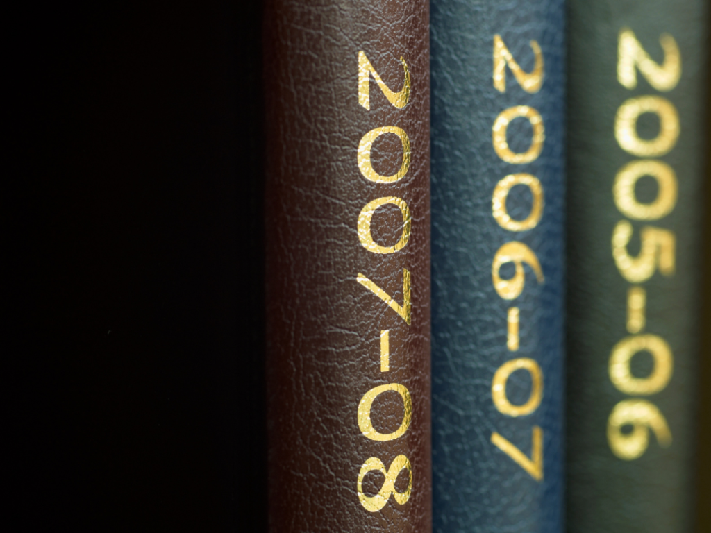 Yearbook covers stacked on a shelf, showing progression of years from past to present