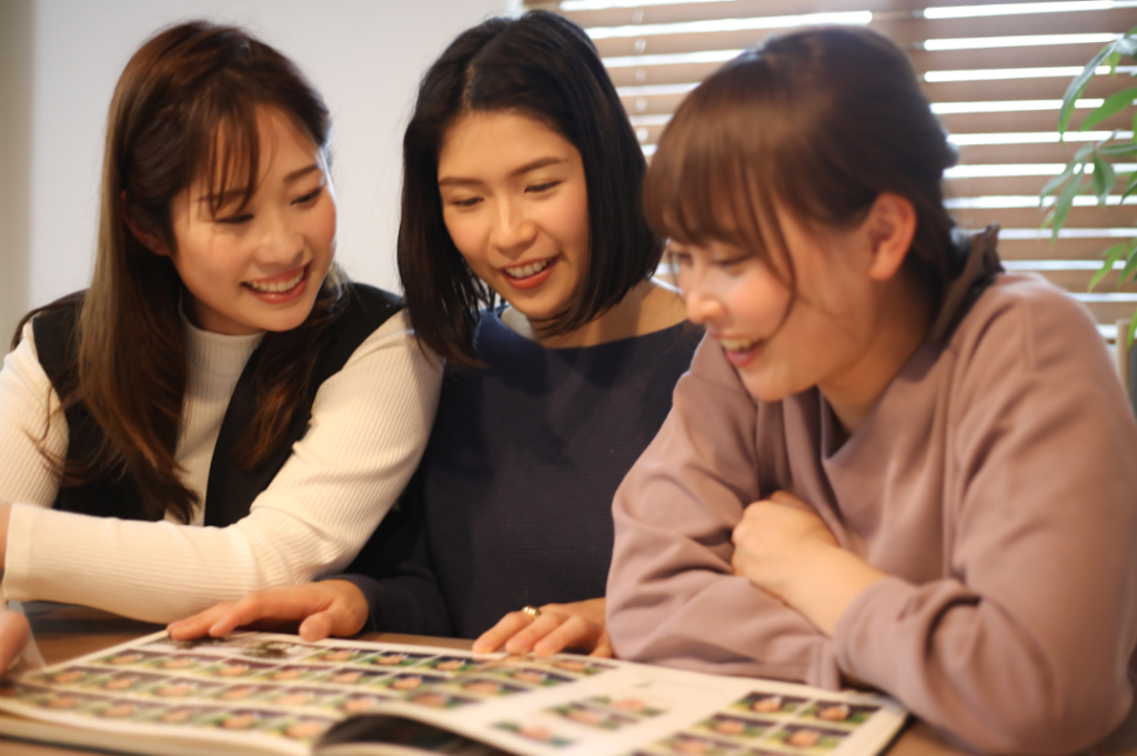 Close-up of friends holding an open yearbook with photos of smiling students from past decades