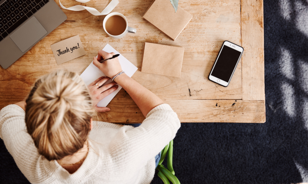 t: a woman writing personalized thank-you letters to K12 alumni