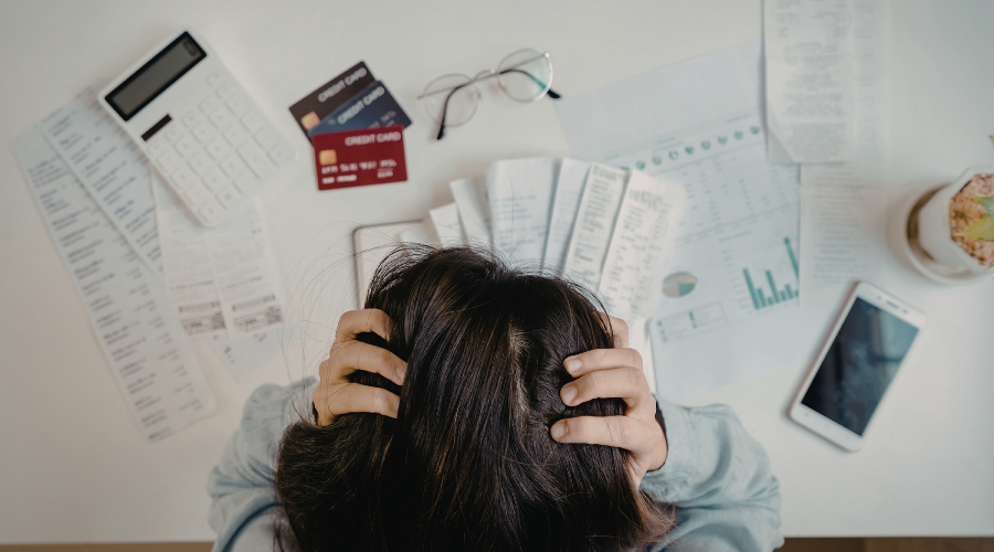 Alt Text- Woman overwhelmed with the amount of paperwork and work that needs done.