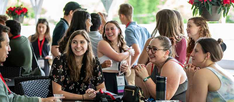 Diverse group of K12 high school alumni smiling and reconnecting at a spring reunion event.