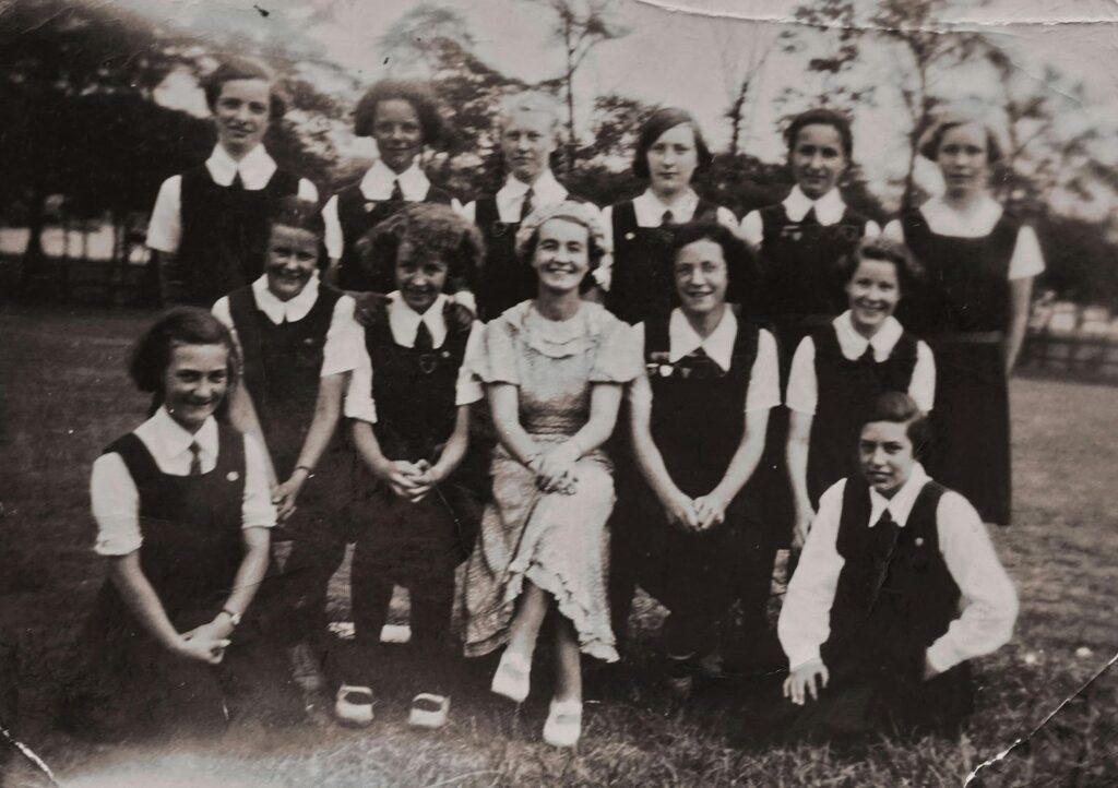 A black and white vintage photograph of a school group posing outdoors, evoking the history and nostalgia of K12 school communities across generations