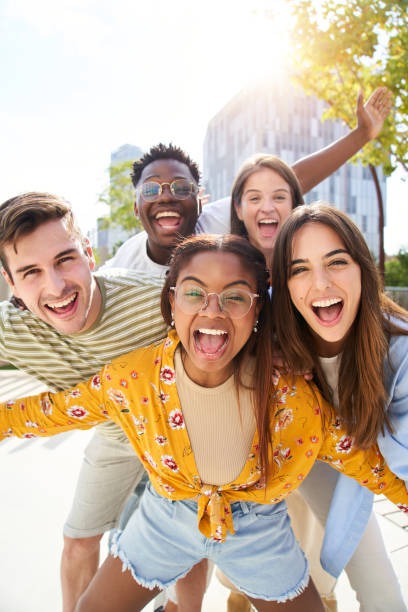 Diverse group of young alumni celebrating together outdoors in the summer