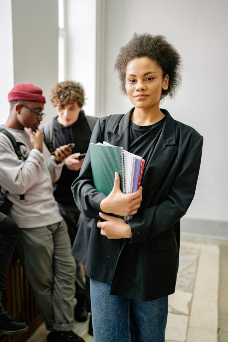 A confident high school student holding notebooks in a school hallway, representing the current students whose futures are shaped by alumni giving and engagement