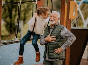 A grandfather and granddaughter sharing a moment at a local playground representing multi-generational alumni in our community.