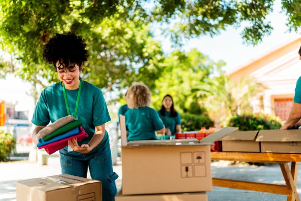High school alumni volunteers holding supply boxes at a community event.