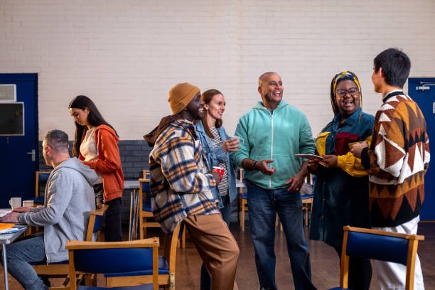 Diverse group of 35-year-old alumni laughing together at a high school reunion.