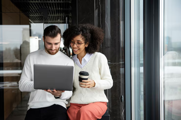 Two people looking at a laptop while smiling.