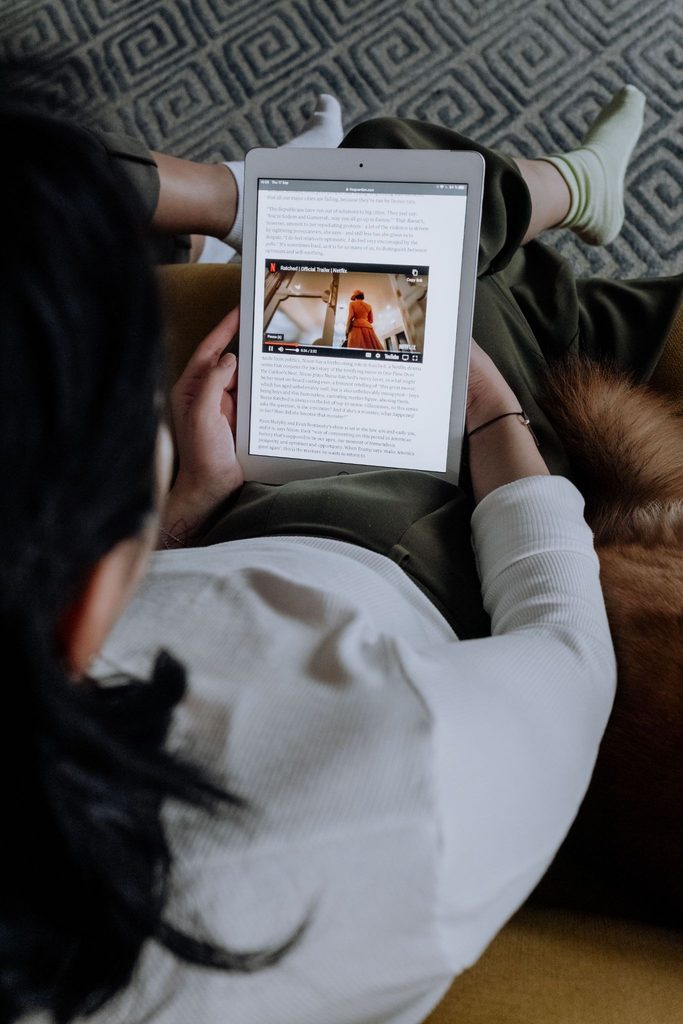 Woman reading an alumni newsletter on a tablet on a couch